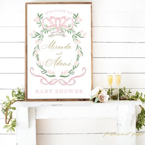 Op de afbeelding: Een roze en groene bloemenkrans met een roze strik en een wit konijn. De krans is op een witte achtergrond met de tekst "Welkom bij Miranda en Adams Baby Shower".