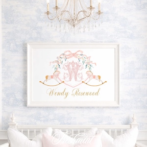 May include: A framed print featuring a pink monogram with floral accents and two rocking horses. The print includes the name "Wendy Rosewood" in gold script. The artwork is displayed on a light blue and white patterned wall.