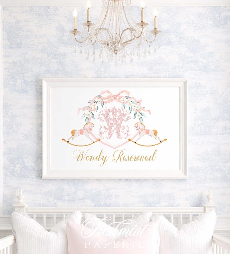 May include: A framed print featuring a pink monogram with floral accents and two rocking horses. The print includes the name "Wendy Rosewood" in gold script. The artwork is displayed on a light blue and white patterned wall.
