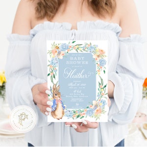 May include: A blue and white baby shower invitation with a watercolour illustration of a bunny rabbit wearing a blue jacket and a bow tie. The invitation features a floral wreath with blue and peach flowers and the text "Come for a Baby Shower in honour of Heather" and "Saturday, March 21, 2020 from 2:00 - 5:00 PM at The Gables 915 Burton Way Beverly Hills, California Registry Amazon & Target 512-555-1212"