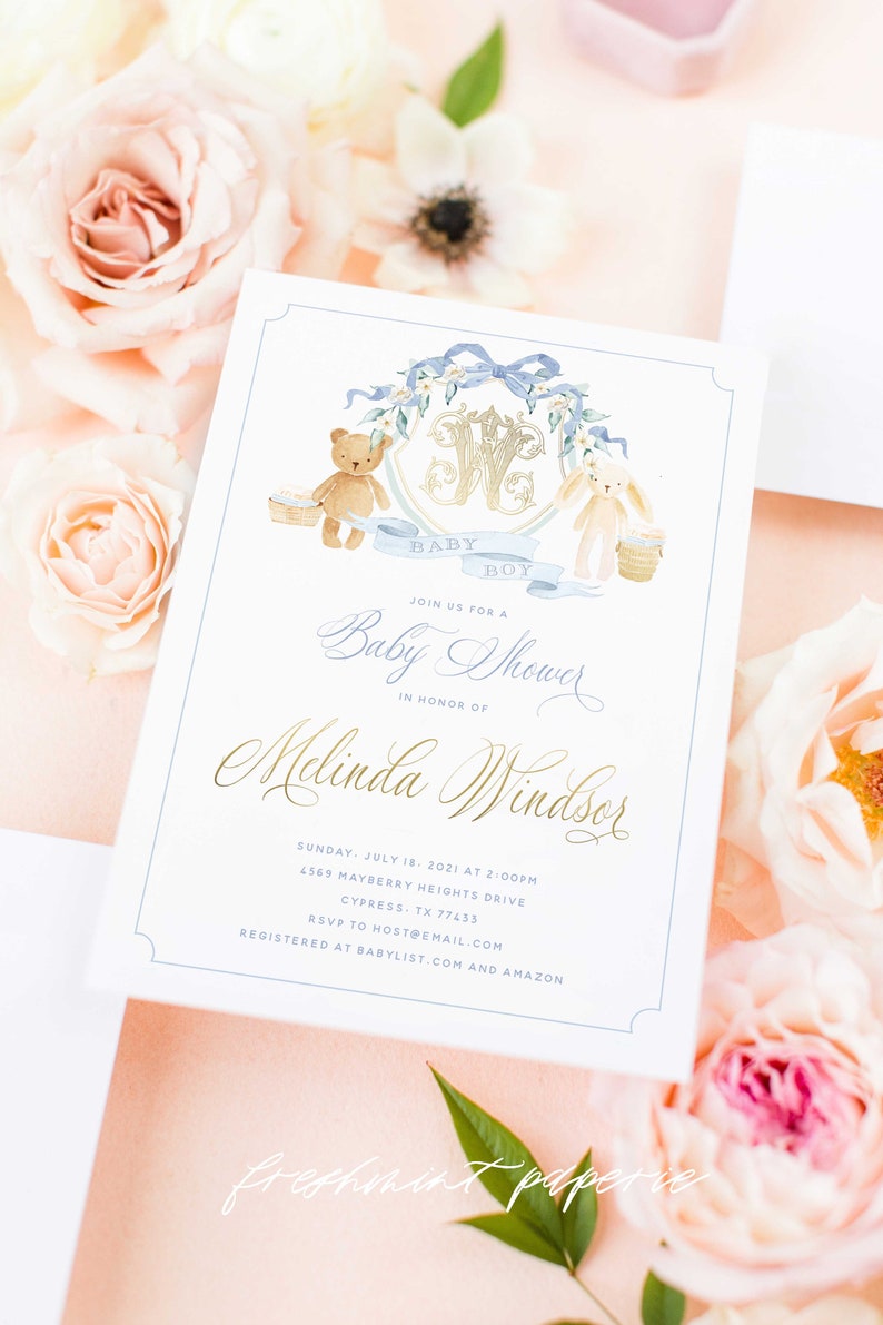 Op de afbeelding: Een witte babyborrel uitnodiging met blauwe en gouden accenten. De uitnodiging heeft een aquarel illustratie van een teddybeer en een konijn die manden vasthouden. De tekst luidt "Baby Boy" en "Doe mee met ons voor een babyborrel ter ere van Melinda Windsor".