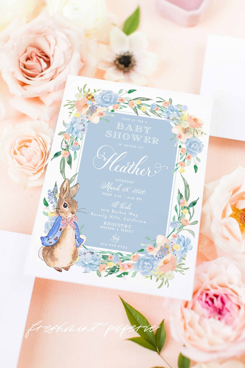 May include: A baby shower invitation with a blue and white floral border. The invitation features a watercolour illustration of Peter Rabbit and the text "Join us for a Baby Shower in honour of Heather, Saturday March 28, 2020 from 2:00 - 5:00 PM at La La, 9018 Burton Way Beverly Hills, California, Registry Amazon & Target, 310 478 1732, freshmint paperie".