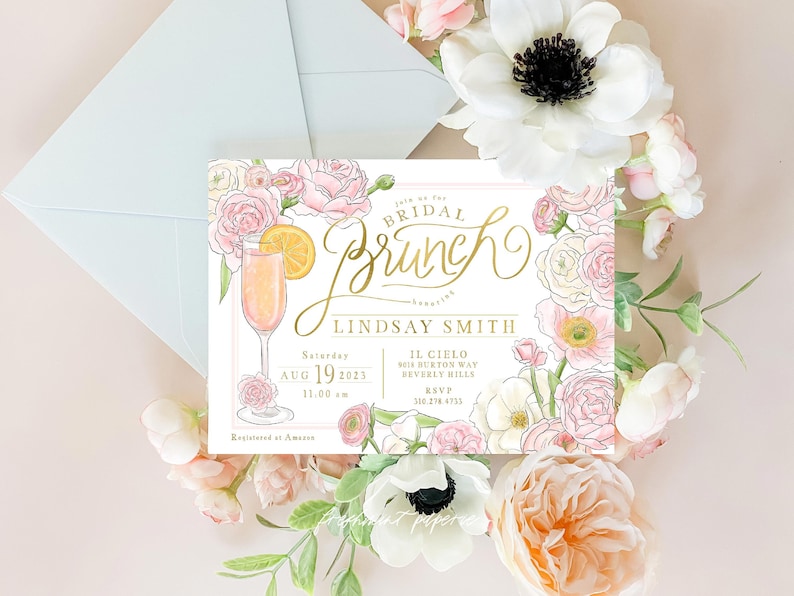 May include: A white bridal brunch invitation with gold lettering. The invitation features a floral design with pink and white flowers and a mimosa cocktail. The text on the invitation reads "Join us for Bridal Brunch honoring Lindsay Smith Saturday Aug 19 2023 11:00 am IL CIELO 9018 Burton Way Beverly Hills RSVP 310.278.4733 Registered at Amazon"