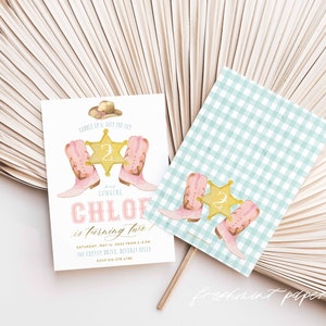 May include: A pink and gold invitation for a girl's second birthday party with a cowboy theme. The invitation features a pair of pink cowboy boots, a gold sheriff's star with the number 2, and a cowboy hat. The text on the invitation reads "Sample of Joy the 122 Cowgirl Chloe is turning two!"