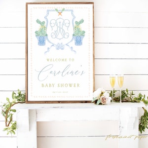 May include: A white and blue baby shower sign with a monogram and the text "Welcome to Caroline's Baby Shower April 20, 2023".