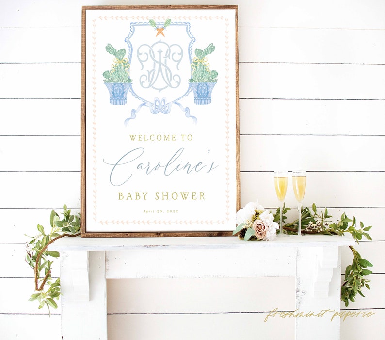 May include: A white and blue baby shower sign with a monogram and the text "Welcome to Caroline's Baby Shower April 20, 2023".