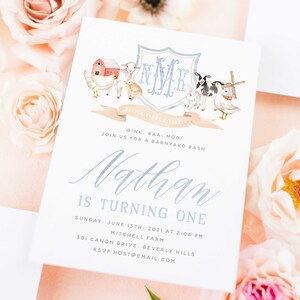 May include: A white invitation with blue text for a barnyard-themed first birthday party. The invitation features a watercolor illustration of a barn, animals, and a windmill. The text reads "Oink, baa, moo! Join us for a barnyard bash. Nathan is turning one. Sunday, June 13th, 2021 at 2:00 PM. Mitchell Farm, 301 Canon Drive, Beverly Hills. RSVP host@email.com."