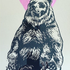 Puede incluir: Una impresión de linóleo en blanco y negro de un oso sentado con un triángulo rosa detrás.