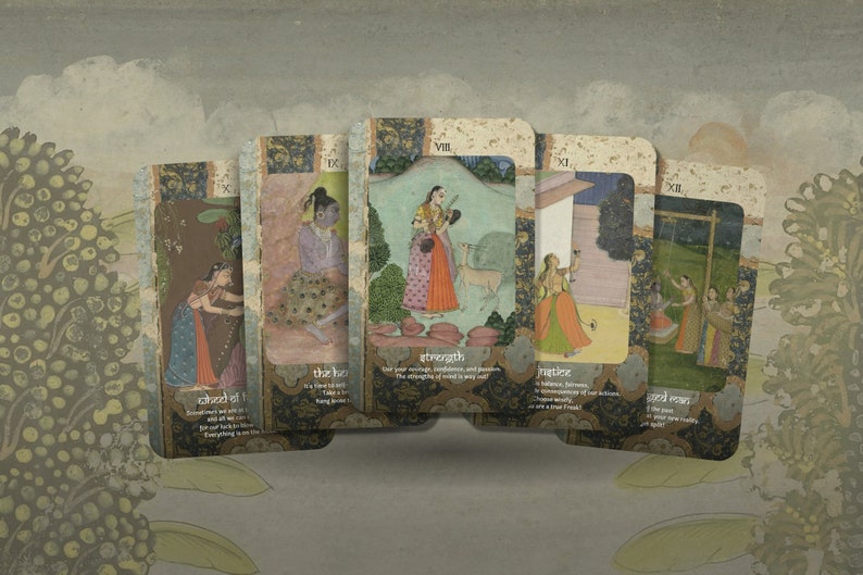 May include: Five tarot cards with colorful illustrations of people in traditional Indian clothing. The cards are laid out in a row, with the top card showing a woman holding a sword. The cards are labeled with Roman numerals and the names of the cards: "Strength", "Justice", "The Hanged Man", "Wheel of Fortune", and "The Lovers".
