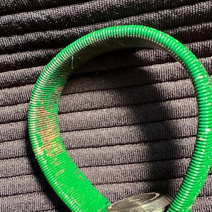 May include: A green watch with a metal face and a flexible, ribbed green band.