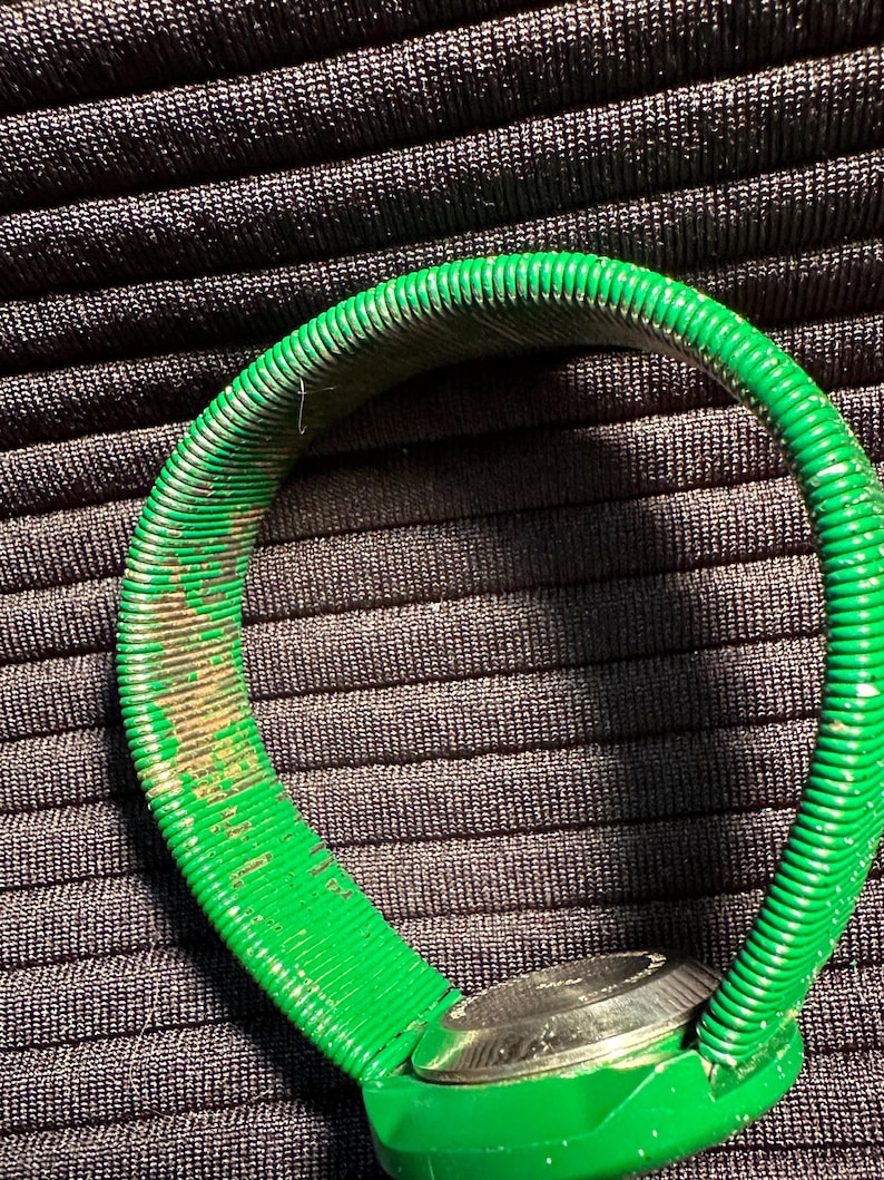 May include: A green watch with a metal face and a flexible, ribbed green band.
