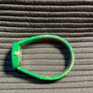 May include: A green watch with a green band. The band is made of a flexible material.