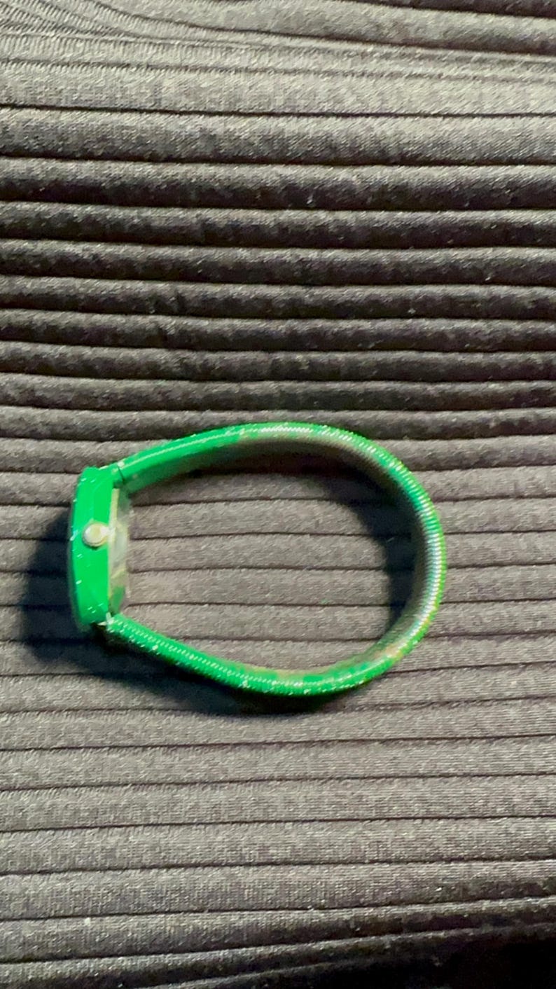 May include: A green watch with a green band. The band is made of a flexible material.