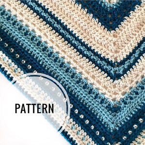 May include: Crocheted pattern in shades of blue and cream, with a geometric design. The word "PATTERN" is displayed in a semi-circle. The crochet work features a textured stitch and small, decorative embellishments.
