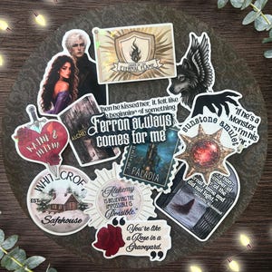 May include: A collection of fantasy-themed stickers featuring illustrations of characters, a wolf, a sunstone amulet, a rose, and text quotes including Ferron always comes for me, Order of the Eternal Flame, and Alchemy is believing the impossible is possible.