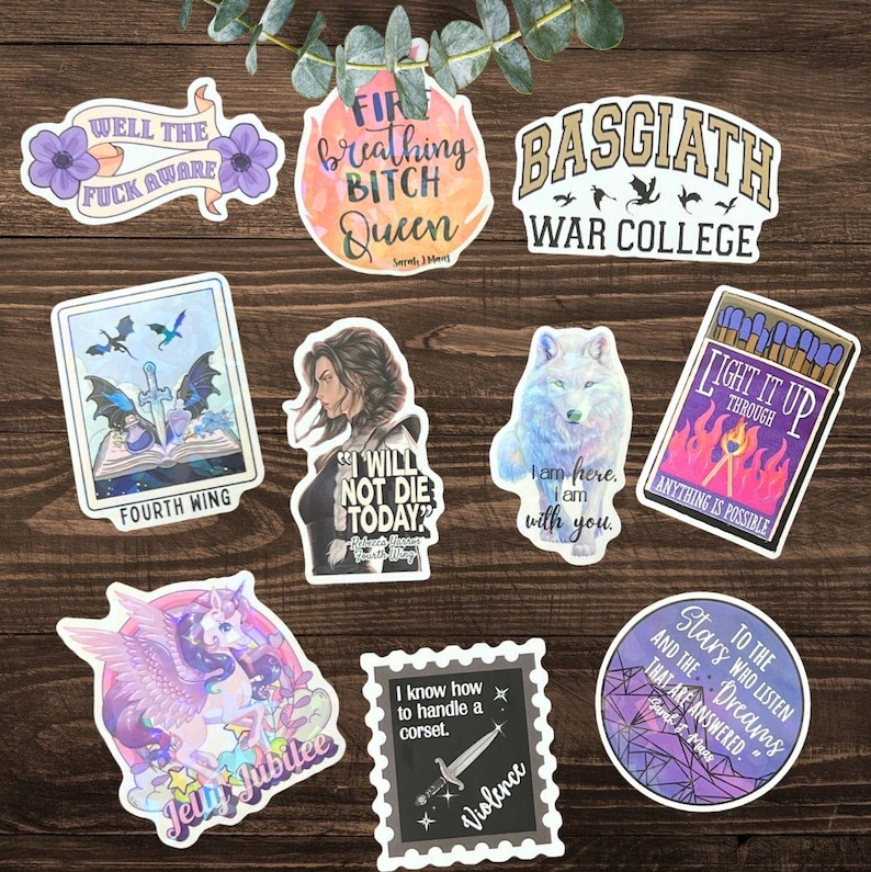 K&ouml;nnte beinhalten: Eine Sammlung von neun Vinyl-Aufklebern mit verschiedenen Motiven wie einem Schwert, einem Wolf, einem Einhorn und Texten wie "Well the fuck aware", "Fire breathing bitch queen", "Basgiath War College", "Fourth Wing", "I will not die today", "Light it up", "Jelly jubilee", "I know how to handle a corset" und "To the stars who listen."