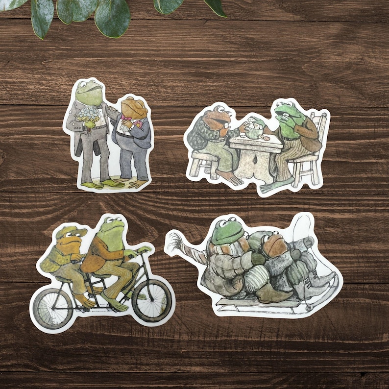 Puede incluir: Conjunto de cuatro pegatinas caprichosas con ranas antropom&oacute;rficas en varias escenas. Una pegatina muestra dos ranas con ropa formal, otra representa ranas en una mesa, una tercera muestra ranas en bicicleta y la &uacute;ltima muestra ranas esquiando.