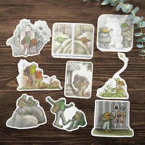 Puede incluir: Un conjunto de pegatinas ilustradas con Rana y Sapo en varias escenas. Las pegatinas muestran a los personajes en diferentes escenarios, incluyendo una casa, una cama y una helader&iacute;a. El texto "That night Frog and Toad were both happy" es visible.