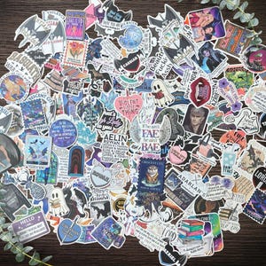 K&ouml;nnte beinhalten: Eine gro&szlig;e Sammlung verschiedener Vinyl-Aufkleber mit diversen Fantasy-Illustrationen, Charakterportr&auml;ts und textbasierten Designs. Die Aufkleber zeigen unterschiedliche Formen, Farben und Motive wie Schwerter, Fl&uuml;gel, Geister und B&uuml;cher.