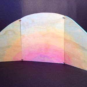 May include: A three-panel wooden backdrop painted with a gradient of light blue, yellow and pink. The panels are hinged together and can be folded for storage.