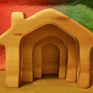 May include: A set of three wooden nesting houses, each with a different size opening. The houses are made of natural wood and have a light brown color.