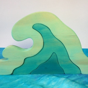 May include: A wooden wave puzzle toy with four interlocking pieces. The wave is painted in shades of green and blue.