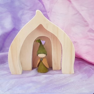 May include: A wooden dollhouse with a heart-shaped opening, featuring a small felt gnome wearing a green hat and cloak standing in the doorway.