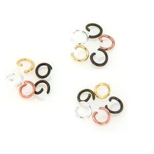 May include: Assortment of jump rings in various colors, including black, silver, gold, and copper. The jump rings are arranged in three groups, with each group containing multiple rings.