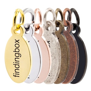 Op de afbeelding: Een set van zes ovale metalen labels met een springring. De labels zijn in goud, zilver, rosé goud, antiek zilver, koper en zwart. Het gouden label heeft de tekst "findingbox" gegraveerd.