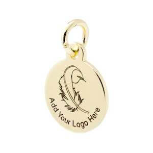 K&ouml;nnte beinhalten: Goldfarbener runder Anh&auml;nger mit Federdesign und dem Text "Add Your Logo Here". Der Anh&auml;nger hat oben eine kleine Schlaufe zum Befestigen an einer Kette. Die Feder ist schwarz ge&auml;tzt.