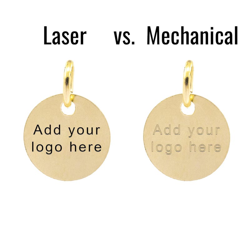 May include: Two gold-colored metal tags with a round shape and a hole at the top. The text "Add your logo here" is engraved on each tag. The tag on the left has a laser engraved inscription, while the tag on the right has a mechanically engraved inscription. The text "Laser vs. Mechanical" is displayed above the tags.