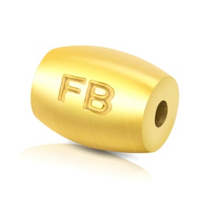 May include: A gold-coloured metal bead with the letters "FB" engraved on the side.