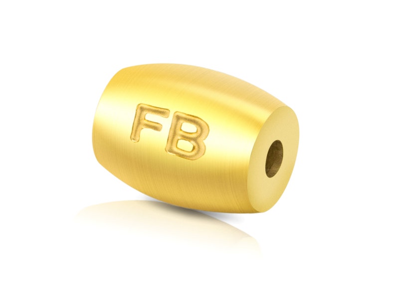 May include: A gold-coloured metal bead with the letters "FB" engraved on the side.