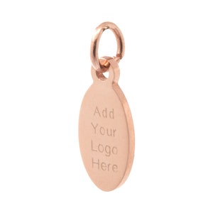 May include: A rose gold oval charm with a jump ring. The charm has the text "Add Your Logo Here" engraved on it.