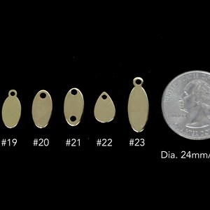 May include: Six different sizes of gold oval metal tags with a hole at the top for hanging. The tags are arranged in order of size from smallest to largest. The smallest tag is about the size of a dime. The largest tag is about the size of a quarter. A U.S. quarter is shown for size comparison. The text "Dia. 24mm/0.95" is also shown.
