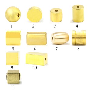 May include: Assortment of 11 gold and brass beads in various shapes and sizes, including round, square, rectangular, and cylindrical beads.