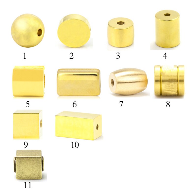 May include: Assortment of 11 gold and brass beads in various shapes and sizes, including round, square, rectangular, and cylindrical beads.