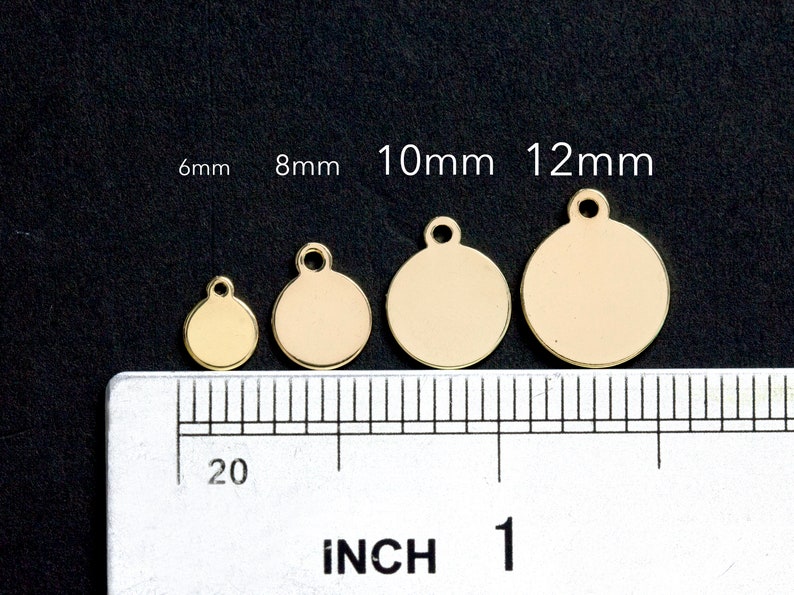 May include: Four gold-colored metal circle charms with a loop at the top. The charms are 6mm, 8mm, 10mm, and 12mm in diameter. A ruler is shown for size reference.