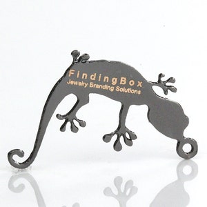 Puede incluir: Soporte de exhibici&oacute;n de joyer&iacute;a en forma de gecko de metal negro con el texto "FindingBox Jewelry Branding Solutions" grabado en el lateral.