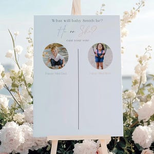 Op de afbeelding: Een wit gender reveal bord op een houten ezel met de tekst What will baby Smith be? He or She? Cast your vote. Het bord bevat twee ronde fotokaders met een verticale lijn en tekstlabels onder elke foto.