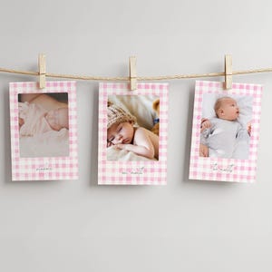 May include: Three baby milestone photo prints hanging from a string with wooden clips. Each print has a pink gingham border and a baby photo. The prints are labeled 'newborn', 'one month', and 'two months' in a script font.