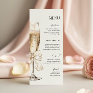 Op de afbeelding: Een verticale menukaart op crèmekleurig papier met een aquarelillustratie van een champagneglas met een crèmekleurig lint om de steel gestrikt. De tekst bevat een lijst met voorgerechten, hoofdgerechten, desserts en dranken.