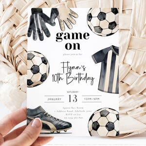 May include: A soccer-themed birthday invitation with watercolor illustrations. The invitation features soccer balls, gloves, a jersey, and a soccer cleat. Text includes "game on," "Flynn's 10th Birthday," and event details.
