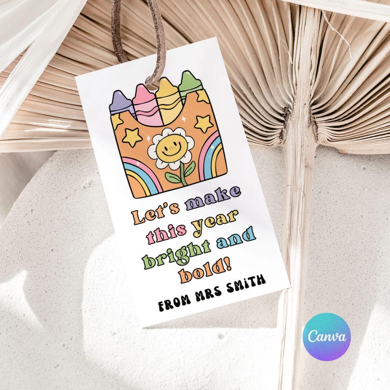 May include: A white gift tag with a colorful illustration of crayons, a smiling flower, and a rainbow. The tag reads "Let's make this year bright and bold!" and "FROM MRS SMITH". A brown string is attached to the top.