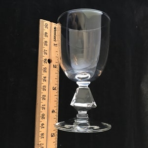 May include: A clear glass wine glass with a diamond-shaped stem and a wide base. The glass is approximately 5 inches tall.