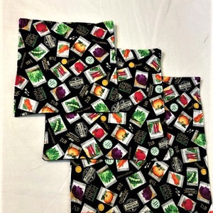 May include: Three black fabric placemats with a repeating pattern of colourful vegetables, fruits, and the text "Farm Fresh Products" and "Organic".