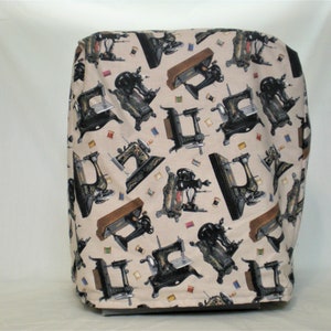 Puede incluir: Una funda de máquina de coser beige con un patrón repetido de máquinas de coser antiguas y carretes de hilo.