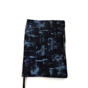 May include: A dark blue and light blue patterned skirt. The skirt has a rectangular shape and a black strap. The fabric has a brushstroke-like design.