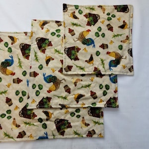 Puede incluir: Tres manteles individuales de tela beige con un patrón repetido de gallos, verduras verdes y bayas rojas en una carretilla.