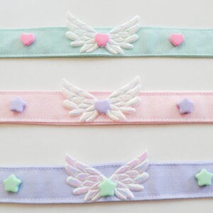 May include: Three pastel colored ribbon chokers with white wings and pastel colored heart and star embellishments.